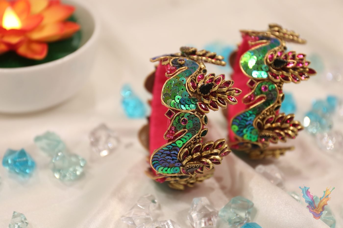 Red peacock bangles displayed with lotus candles and crystals