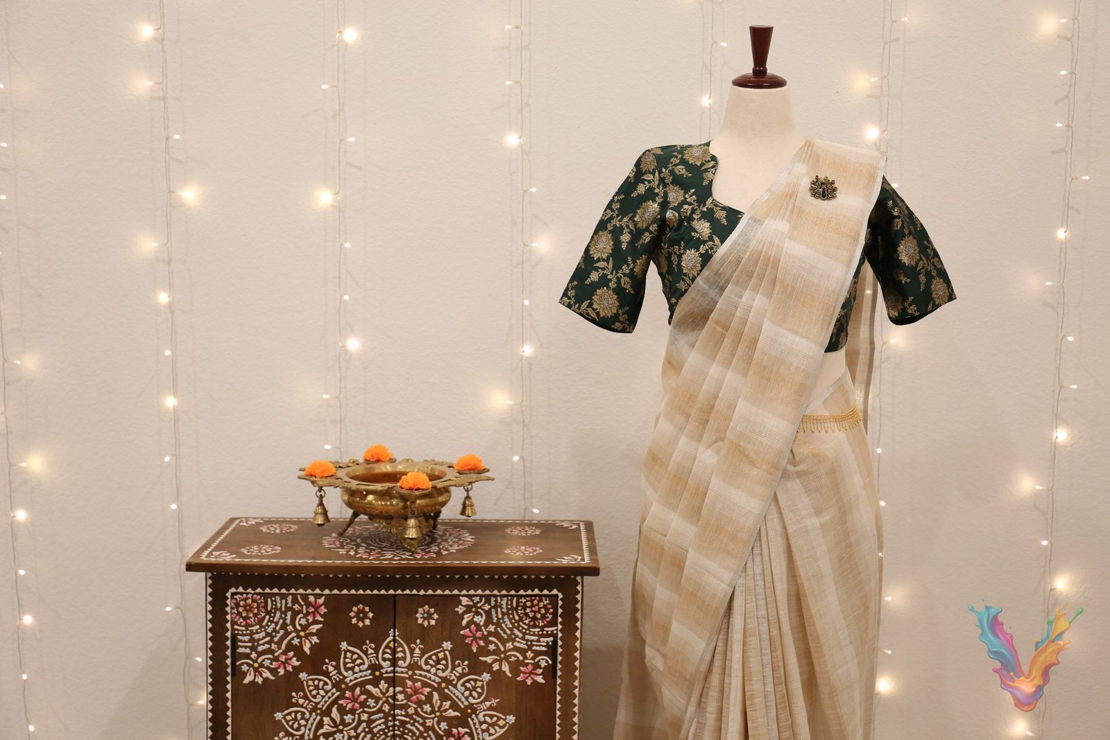 An ivory silk saree with a green brocade blouse draped on a mannequin among fairy lights